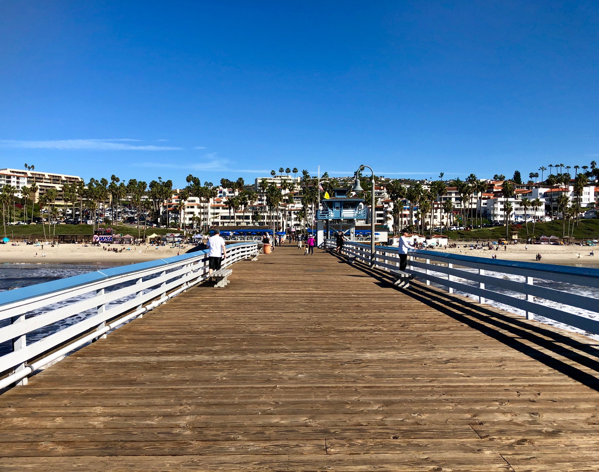 People walking along pier on beautiful day
